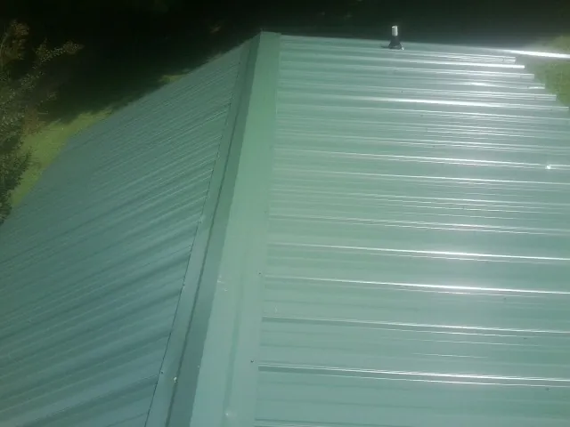 New green metal panels meeting at the ridge of a roof — Flat Roof Repair work by our crew in Ridgefield