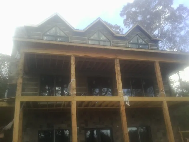 Dormers and porch framing on a large log home under construction — Roof Coating work by our crew in Ridgefield